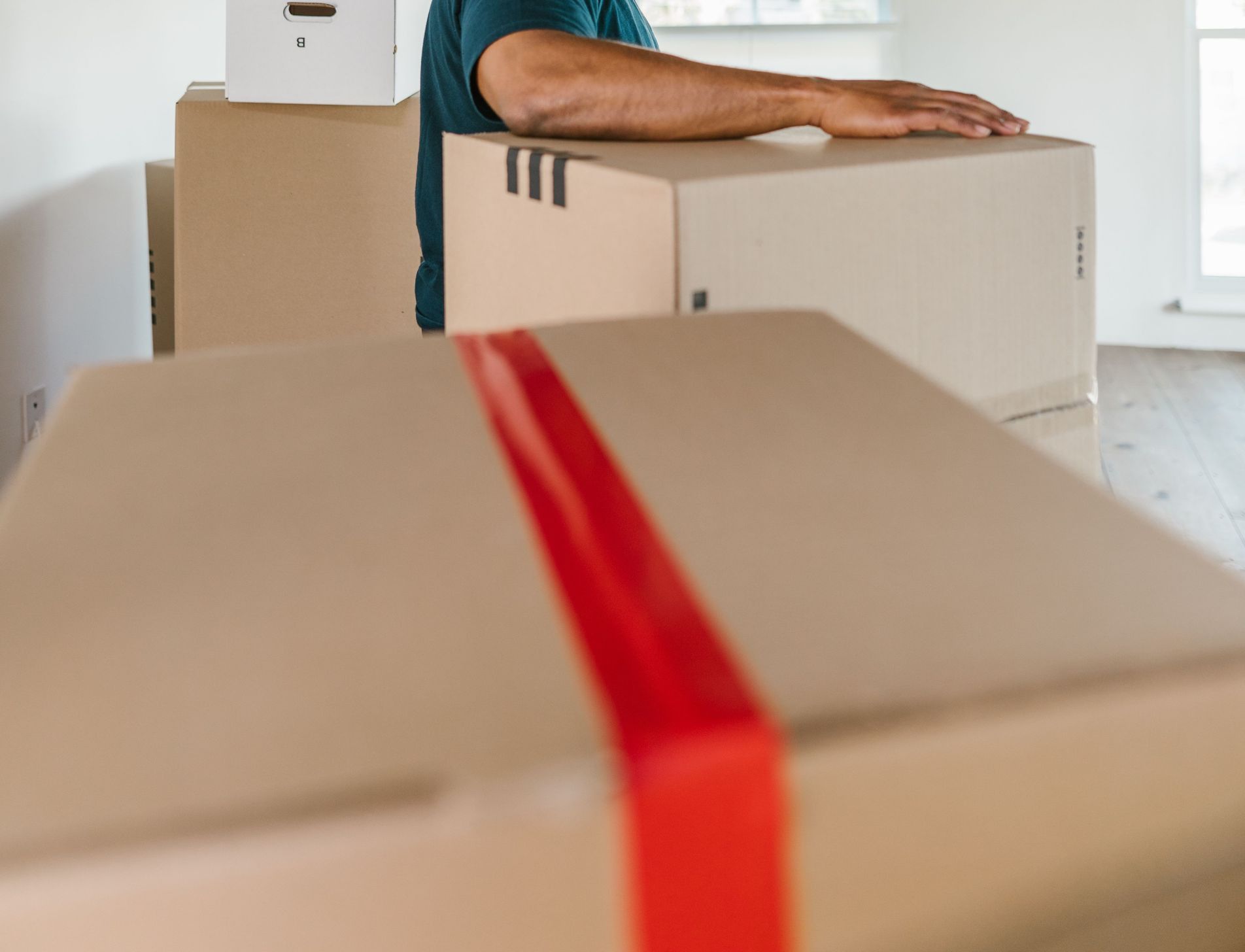 Man handling moving boxes in a spacious, modern room during relocation.