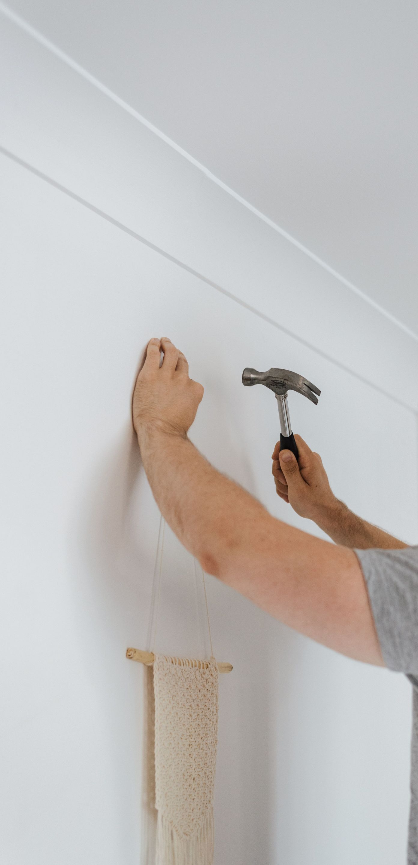 Side view of bearded craftsman with hammer putting decoration on wall during renovation works